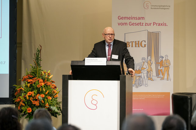 Das Bild zeigt Johannes Fuchs, den Präsidenten des Deutschen Vereins für öffentliche und private Fürsorge, hinter einem rednerpult auf der Bühne.