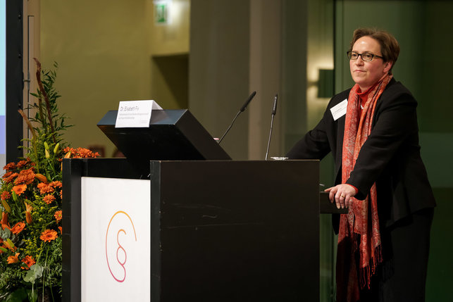 Das Bild zeigt Dr. Elisabeth Fix, Referentin beim Deutschen Caritasverband, hinter dem Rednerpult auf der Bühne.