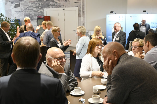 Das Foto zeigt Teilnehmende der Veranstaltung bei Kaffee und Snacks im Gespräch.