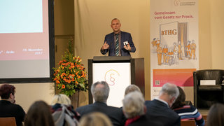 Das Bild zeigt Dirk Lewandrowski, LVR, der im Forum 4 zu "Trennung von Fach- und existenzsichernden Leistungen", referierte, vorne hinter dem Rednerpult auf der Bühne.
