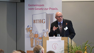 Das Bild zeigt Johannes Fuchs während seiner Rede auf der Bühne stehend hinter einem Rednerpult.